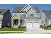 Charming two-story home showcasing beautiful stonework, a two-car garage, and a well-manicured lawn at 737 W Holly Springs Rd, Holly Springs, NC 27540