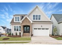 Beautiful two-story home featuring a two-car garage, manicured lawn, and brick-accented entryway at 749 W Holly Springs Rd, Holly Springs, NC 27540