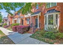 Charming brick townhomes with manicured landscaping and inviting front entrances on a sunny day at 110 Tressel Way, Durham, NC 27707