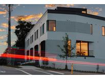 Modern townhome showcasing unique architecture and dynamic lighting against a beautiful sunset backdrop at 1303 Chamblee Hill Ct, Raleigh, NC 27608