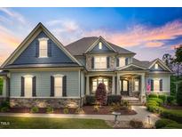 Beautiful two-story home featuring manicured landscaping, stone accents, and inviting covered front porch at 1308 Green Oaks Pkwy, Holly Springs, NC 27540
