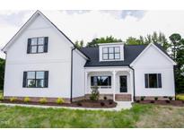 Charming two-story home featuring white siding, black trim, inviting front porch and a well-manicured lawn at 155 Diamond Creek Dr, Zebulon, NC 27597