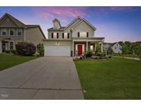 Charming two-story home with a well-manicured lawn, a red door, and an attached two-car garage at 2429 Follow Me Way, Raleigh, NC 27610