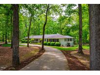 Stunning exterior view of a white home surrounded by lush greenery and a winding driveway at 3804 Nottaway Rd, Durham, NC 27707