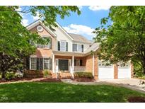 Charming brick and siding two-story home with lush green lawn, mature trees, and a welcoming front porch at 9117 Meadow Mist Ct, Raleigh, NC 27617