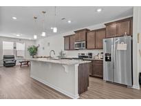 Spacious kitchen features a large island, granite countertops, stainless steel appliances, and wood-look flooring at 987 Parkstone Towne Blvd, Knightdale, NC 27545