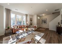 Bright living room features a leather sofa, large windows, and wood-look flooring at Lot 5 Cooper St, Sanford, NC 27330