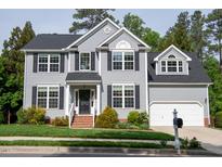 Charming two-story home boasts gray siding, black shutters, lush landscaping, and attached two-car garage at 101 Worsham Dr, Chapel Hill, NC 27516