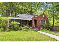 Charming brick home with a well-manicured lawn, flower beds, and a cozy screened-in porch at 1113 Alabama Ave, Durham, NC 27705