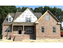 New brick home with white trim windows and a covered porch, set against a backdrop of mature trees at 1589 S Old Carriage Rd, Rocky Mount, NC 27804