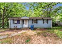 Charming single-story home with light blue siding and traditional shutters, nestled amongst mature trees at 2733 Thelma St, Durham, NC 27704