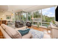 Bright living room with hardwood floors, large windows showcasing tree views, and a comfortable seating arrangement at 3210 Environ Way, Chapel Hill, NC 27517