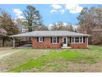 Charming brick home with a covered carport and a well-manicured lawn at 3402 Pat Tilley Rd, Bahama, NC 27503