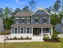 Charming blue two-story home featuring a welcoming front porch and manicured landscaping at 3866 Keohane Dr, Durham, NC 27705