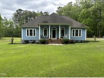 Charming one-story home featuring a light blue exterior, covered front porch, and well-manicured lawn at 4793 Overhills Rd, Spring Lake, NC 28390