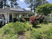 Charming home featuring solar panels, a front porch, and a lush garden at 5404 Drum Inlet Pl, Raleigh, NC 27610