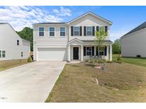 Charming two-story home features a well-maintained lawn, attached garage, and inviting front porch at 80 Spotted Bee Way, Youngsville, NC 27596