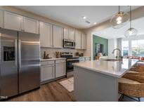 Modern kitchen with stainless steel appliances, gray cabinets, and a stylish island with seating at Lot 7 Cooper St, Sanford, NC 27330