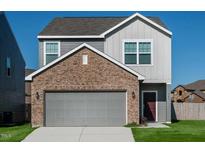 Two-story home features a gray exterior, brick accents, a two-car garage, and a manicured lawn at 1215 Pond Overlook Drive, Nashville, NC 27856