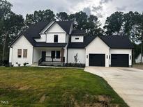 Beautiful two-story home featuring a black roof, white paint, and an attached two car garage at 123-125 Ottawa Dr., Louisburg, NC 27549