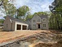 New home features a stately gray brick exterior, attached two-car garage, and professionally landscaped front yard at 1404 Song Bird Crest Way, Raleigh, NC 27613