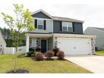Charming two-story home with stone accents, a two-car garage, and a well-manicured front lawn at 608 Crackling Ct, Zebulon, NC 27597