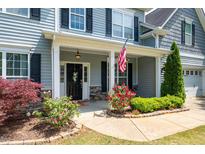 Charming front porch with stone accents, black door, and beautiful landscaping at 6901 Rex Rd, Holly Springs, NC 27540