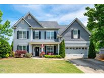 Charming two-story home with beautiful landscaping, complemented by an inviting front porch and well-maintained lawn at 6901 Rex Rd, Holly Springs, NC 27540
