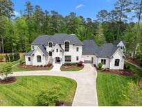 Stunning two-story white brick home featuring a lush green lawn and circular driveway at 1416 Bailey Hill Dr, Raleigh, NC 27614