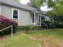 Charming home featuring a covered entryway, traditional siding, and lush landscaping with flowering shrubs at 1812 House Ave, Durham, NC 27707