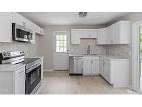 Modern kitchen features stainless steel appliances, white cabinets, countertops, and subway tile backsplash at 1903 Meadowbrook St, Sanford, NC 27330
