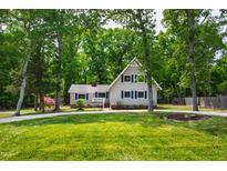 Charming two-story home with lush green yard and mature trees, plus a paved driveway and welcoming front porch at 1915 Redding Ln, Durham, NC 27712