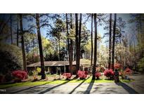 Charming home surrounded by mature trees and flowering shrubs in the front yard at 2100 Possum Trot Rd, Wake Forest, NC 27587