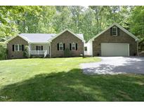 Charming brick home with a well-manicured lawn and attached two-car garage with fresh green foliage at 320 Delvin Lane Ln, Hillsborough, NC 27278