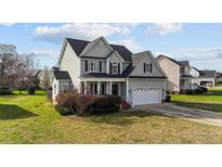 Charming two-story home with a welcoming front porch and a well-manicured lawn at 323 Windgate Dr, Clayton, NC 27527