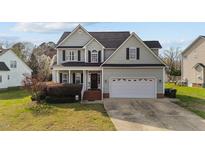 Charming two-story home with a well-manicured lawn and attached two car garage at 323 Windgate Dr, Clayton, NC 27527
