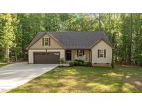 Charming single Gathering home showcasing a manicured lawn, rocking chairs, and attached garage at 4005 Colleen Way, Kittrell, NC 27544