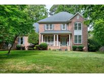 Charming two-story brick home with a covered porch and lush front lawn surrounded by mature trees at 5112 Wolcott Ct, Fuquay Varina, NC 27526
