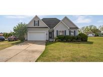 Charming gray home with manicured lawn, complemented by a two-car garage and mature landscaping at 106 Jj Dr, Benson, NC 27504