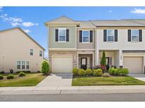 Charming townhome featuring a stone facade, attached garage, and well-manicured landscaping at 1141 Amber Shadow Dr # 101, Durham, NC 27703