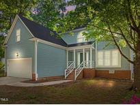Charming home features a two-car garage and a welcoming front porch with white railings at 206 Swiss Lake Dr, Cary, NC 27513