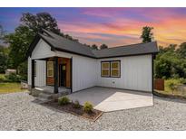 Charming home featuring a black roof, white siding, a cozy front porch, and a gravel yard at 2616 Wedgedale Ave, Durham, NC 27703