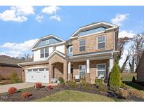 Charming brick two-story home featuring blue accents, manicured landscaping, and a cozy front porch at 330 Macallan Dr, Burlington, NC 27215