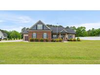 Charming brick and vinyl home with lush green lawn and manicured landscaping at 3345 Little Creek Church Rd, Clayton, NC 27520