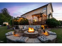 Inviting backyard with a stone fire pit, seating area, and pergola-covered deck, perfect for outdoor gatherings at 48 Falling Oak Ct, Clayton, NC 27520