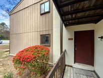 Charming home exterior with a cozy entryway, red door, and blooming azalea bush at 5078 Flint Ridge Pl, Raleigh, NC 27609