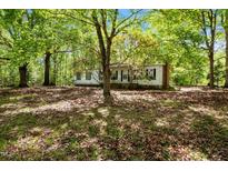 Quaint single-story home with brick chimney nestled among mature trees on a spacious lot at 606 Dennys Store Rd, Roxboro, NC 27574