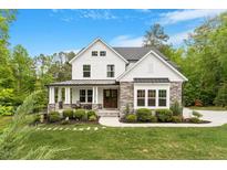 Beautiful two-story home with stone accents, a charming front porch, and lush landscaping at 66 Romie Ct, Pittsboro, NC 27312