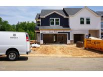 New construction townhome exterior showcasing the garage and uninstalled features under a cloudy sky at 1041 Winding Spring Dr, Mebane, NC 27302