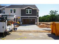 New construction with two-car garage, neutral colors, and landscaping in progress on a sunny day at 1053 Winding Spring Dr, Mebane, NC 27302